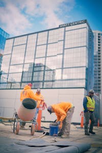 Construction workers in orange vests are working on a building
